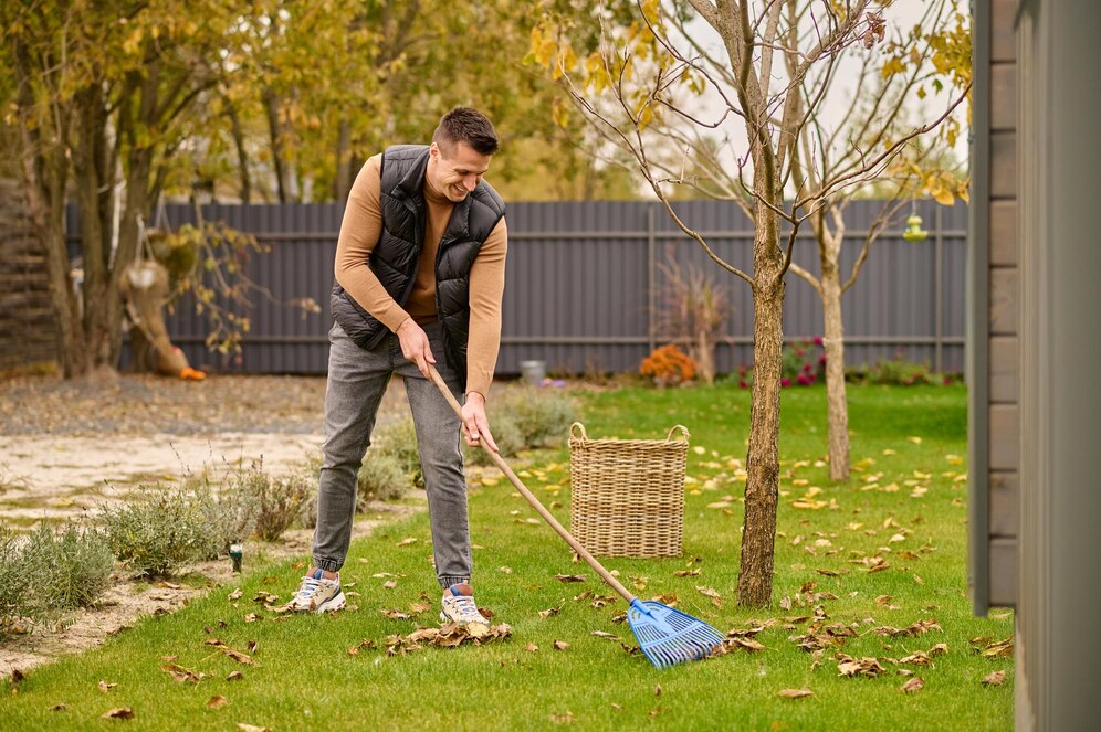 joyful-man-shoveling-leaves-with-garden-tools_259150-59028